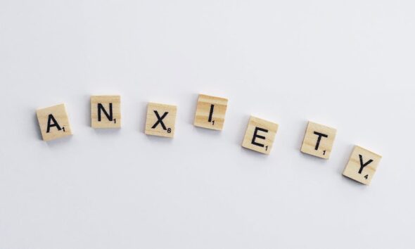 Wooden tiles on a white background spell anxiety, symbolizing mental health awareness.