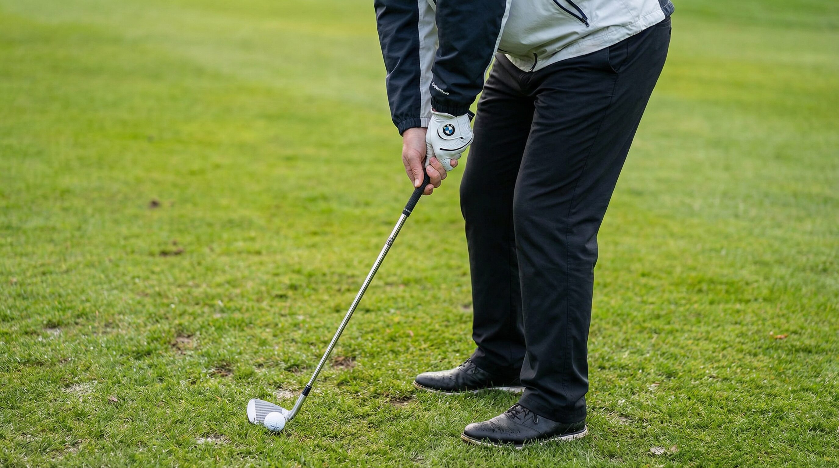 A golfer demonstrating proper ball position for a low wind shot, with the ball positioned back in the stance.