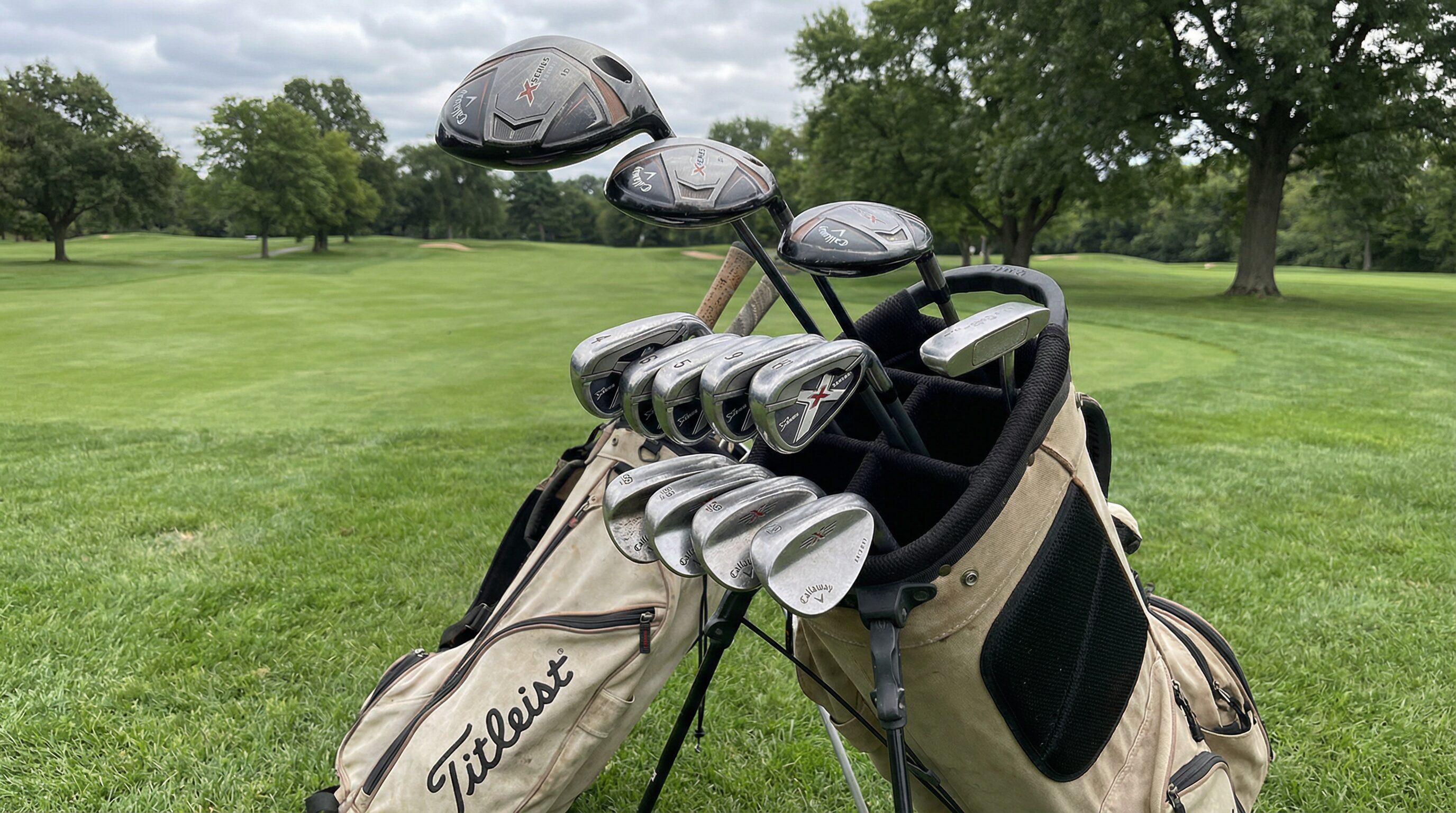 A golfer inspecting a used driver in a golf shop, checking the grip and clubface for wear.