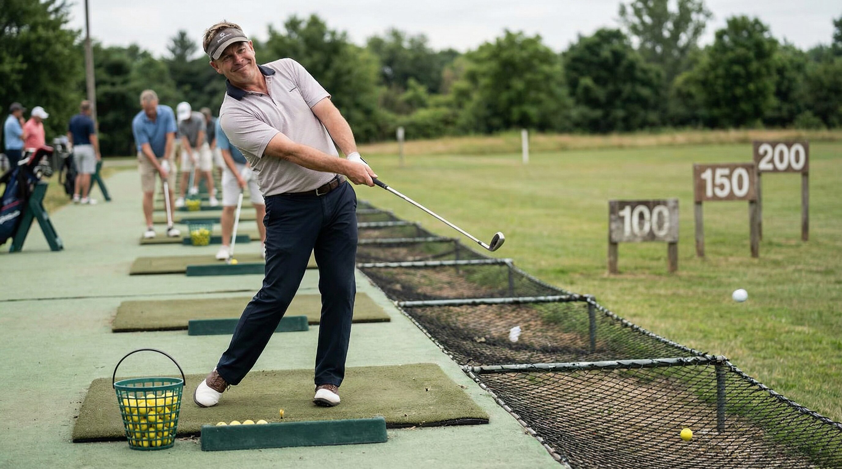 A golfer on the range hitting balls with a satisfied expression, imagining their range performance is better than it actually is.
