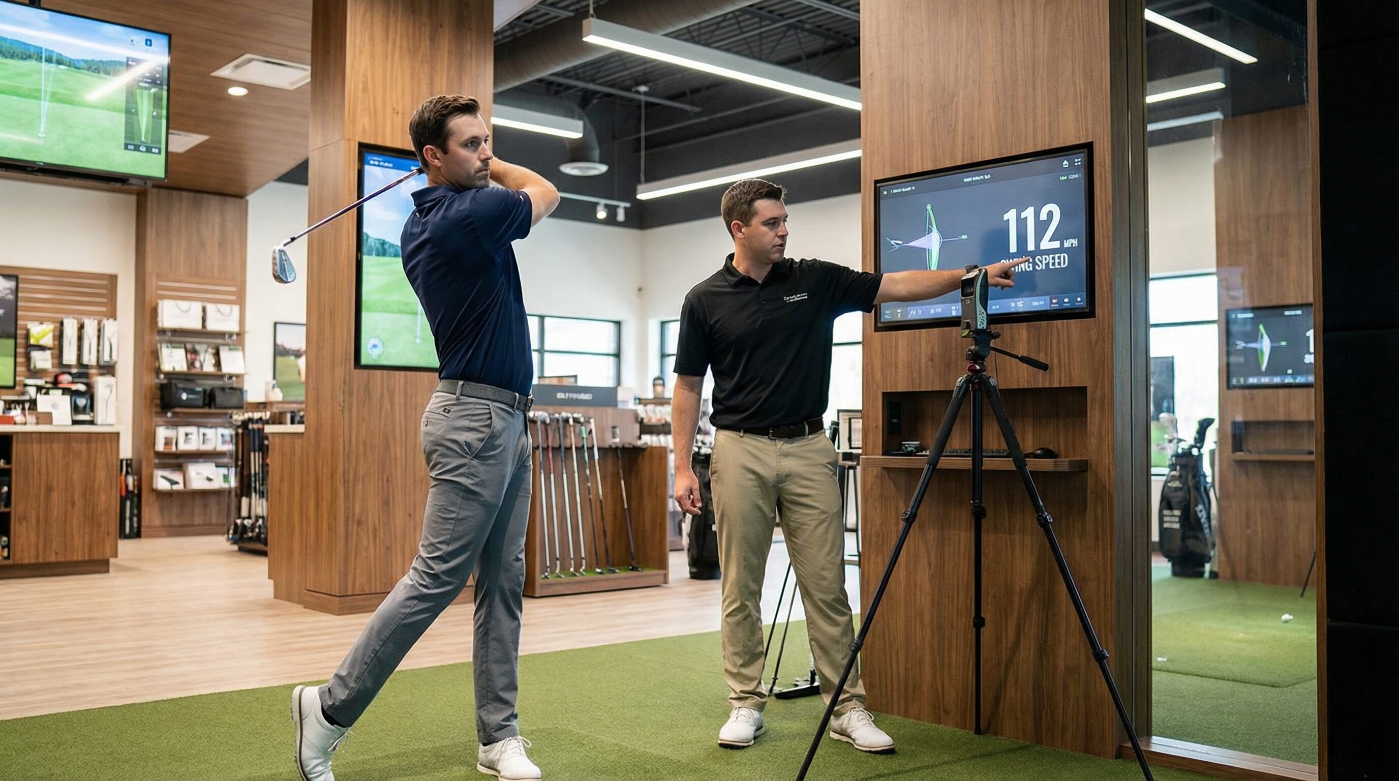 A golfer on a launch monitor at a golf shop, getting their swing speed measured by a professional.