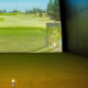 Best home golf simulator 2026 bay with an impact screen, projected course image, and indoor turf.