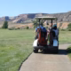 Two golfers riding a cart along a course path, illustrating golf scramble rules etiquette.