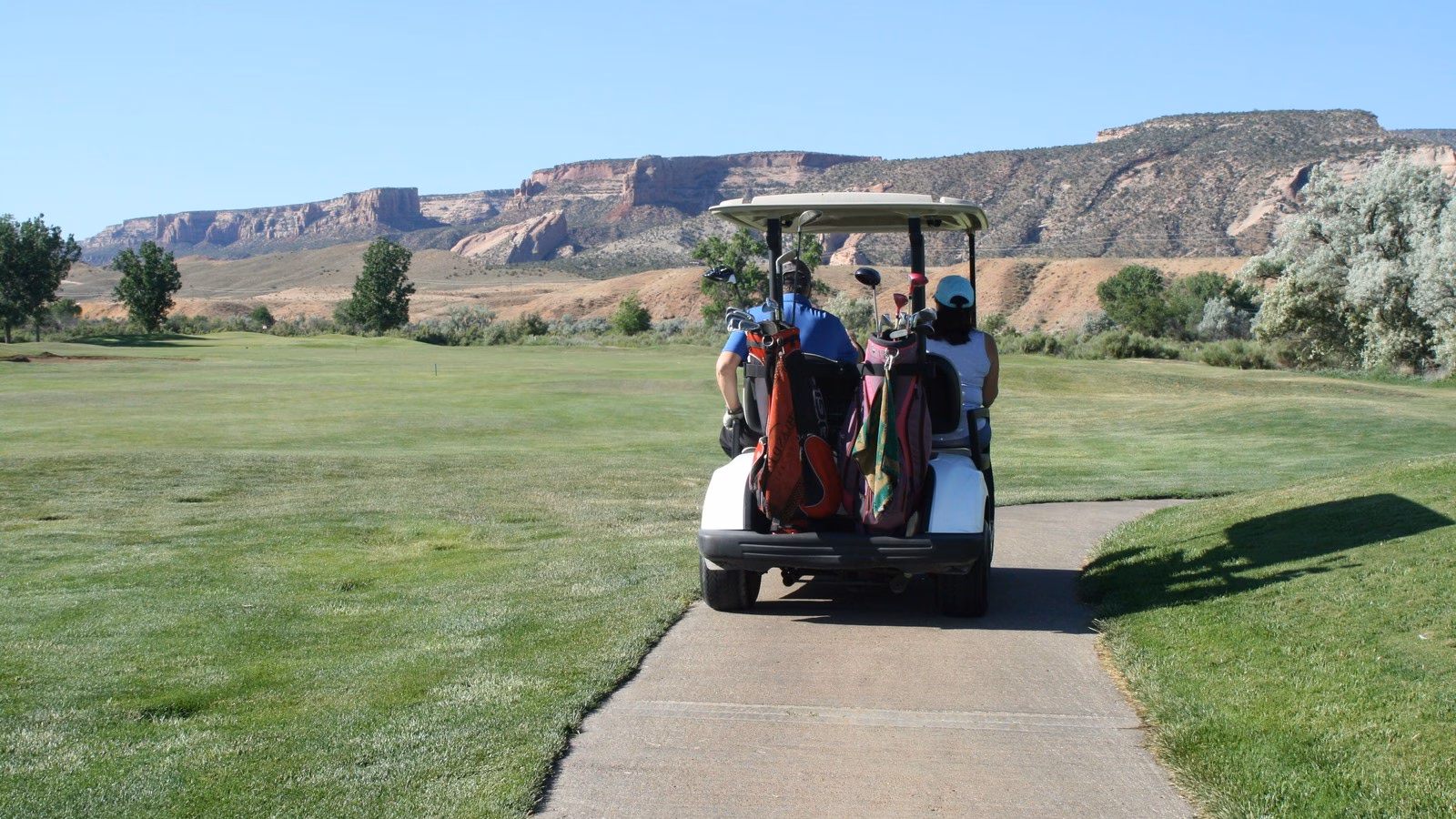 Two golfers riding a cart along a course path, illustrating golf scramble rules etiquette.
