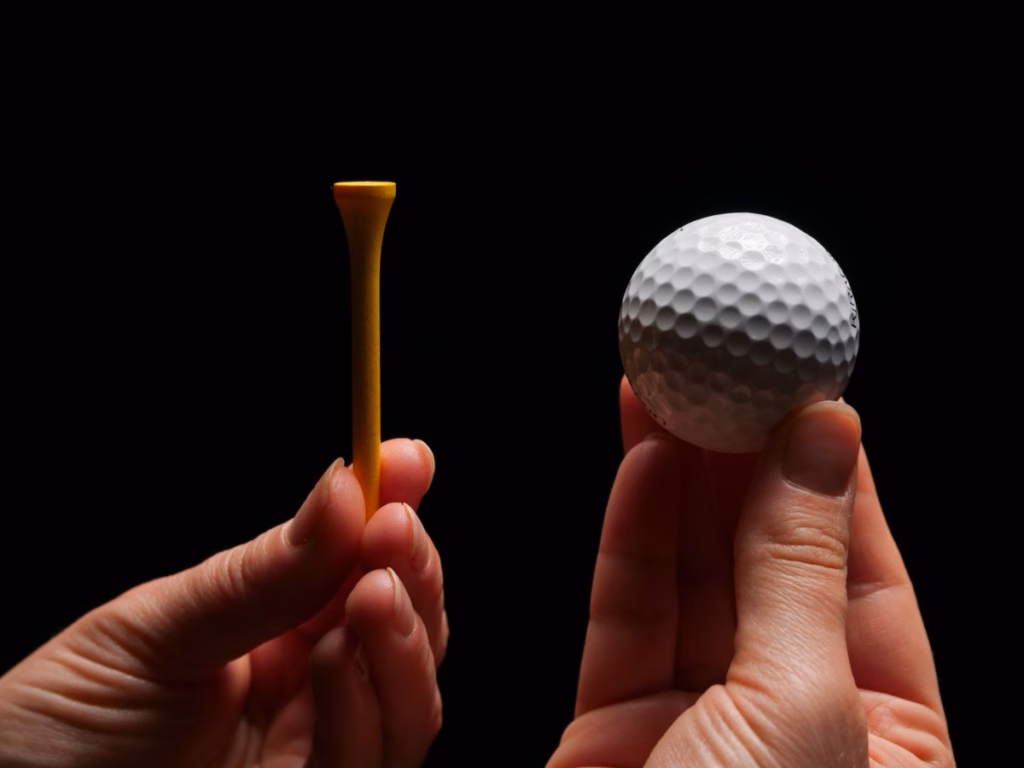 Golf ball and tee in hand, a close-up for a golf tournament scoring app setup.